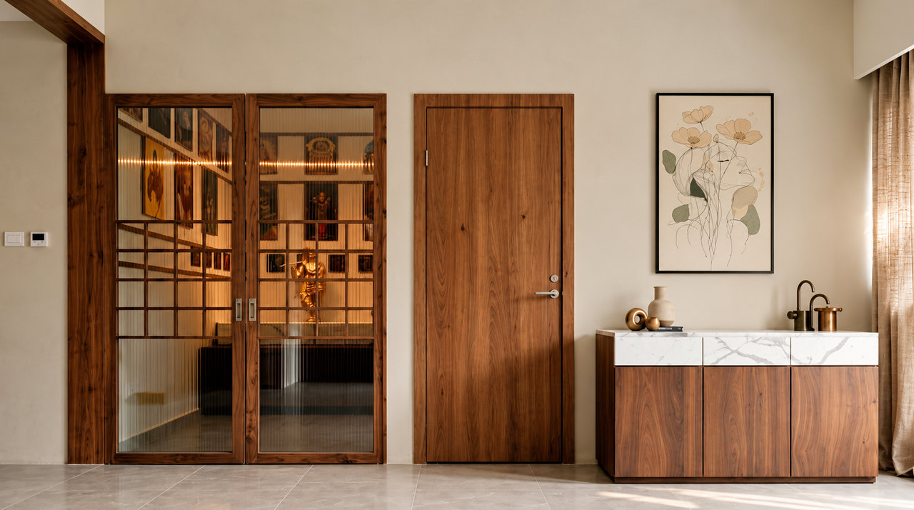 Pooja room behind walnut-framed fluted glass doors, beside a marble-top walnut console with brass accents